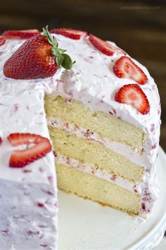 a cake with white frosting and strawberries on top is cut in half to show the layers