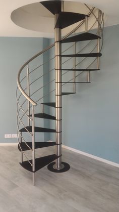 there is a spiral staircase in the corner of this room with blue walls and wood flooring