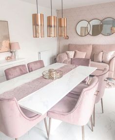 a dining room with pink chairs and a white table surrounded by mirrors on the wall