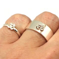 two silver rings with initials on them sitting on top of each other's fingers