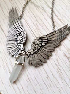 A light, intricate piece that can complete any fantasy lovers' look, this angel wings necklace is the perfect gift for lovers of all winged things.This beautiful angel wings necklace is carefully cut and engraved with detailed veining in special marbled acrylic, inspired by the shape of feathered wings and the characters of crescent city. Each feather is detailed and outlined in silver and black after being placedJoining each pair of feathered wings is a beautiful glass pingent with a light grey Metal Wing-shaped Jewelry Gift, Bohemian Winged Jewelry For Gifts, Angel Wings-shaped Jewelry As Gift, Angel Wings-shaped Jewelry For Gifts, Angel Winged Jewelry For Gifts, Angel Wings Jewelry Gift, Winged Engraved Jewelry For Gifts, White Angel Wings Jewelry As Gift, Silver Angel Wings Necklace