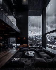 a living room filled with lots of black furniture and large windows overlooking the mountain range