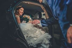 a bride and groom are sitting in the back of a car holding each other's hands