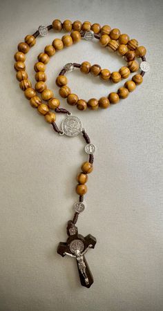 "This beautiful Rosary is made of brown  cord, 10mm wood beads and 2\" crucifix" Adjustable Crucifix Jewelry With Wooden Beads, Adjustable Wooden Bead Crucifix Jewelry, Brown Cross-shaped Rosary With Wooden Beads, Brown Wooden Beaded Cross Rosary, Brown Beaded Rosary With Cross Shape, Brown Beaded Cross Rosary, Brown Beaded Cross-shaped Rosary, Brown Cross Rosary In Spiritual Style, Brown Cross-shaped Spiritual Rosary