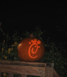 a carved pumpkin sitting on top of a wooden bench