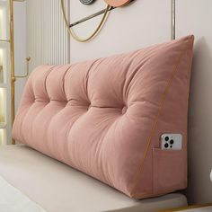 a pink futon couch with an electronic device on the armrests in front of it