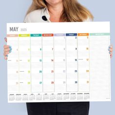 a woman holding up a calendar for the month on her face and smiling at the camera