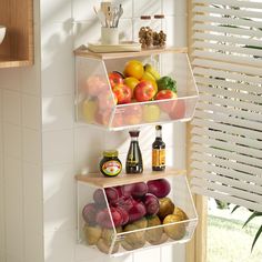 three shelves filled with fruit and condiments on top of a tiled wall next to a window