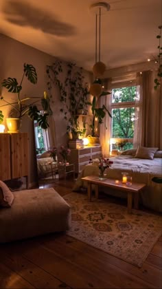 a living room filled with furniture next to a window covered in plants and candles at night