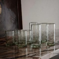 five glasses sitting on top of a counter next to each other in front of a mirror