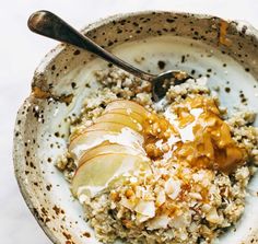 a bowl filled with oatmeal and apples on top of a white table