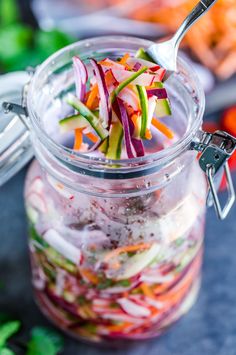 a glass jar filled with sliced vegetables on top of a blue countertop next to other food