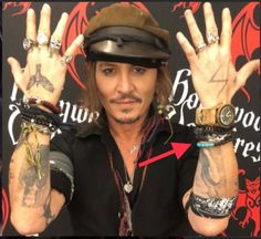 a man with his hands in the air and two rings around his wrists, wearing a hat