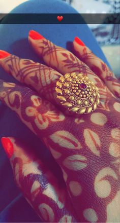 a woman's hand with red fingernails and gold ring on her left hand, in front of a blue background