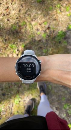 a person wearing a watch on their arm with grass and trees in the back ground