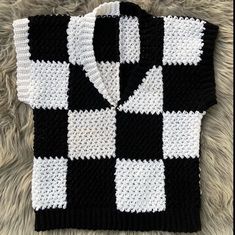 a black and white crocheted sweater laying on top of a rug