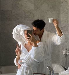 a man and woman are taking a selfie in the bathroom while holding a cup