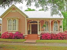 a pink house with flowers in the front yard