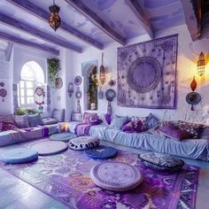 a living room filled with lots of purple and white furniture on top of a rug