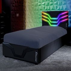 a bed with a black headboard and colorful lights on the wall behind it in a room