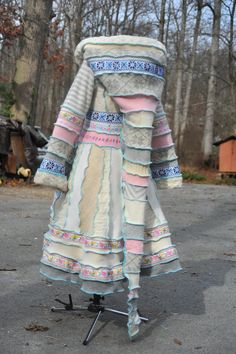 a dress that is sitting on a stand in the middle of a parking lot with trees behind it