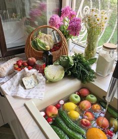 an assortment of fruits and vegetables are on the counter top in front of a window