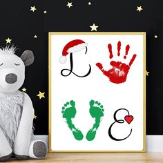 a white teddy bear sitting next to a framed poster with handprints on it