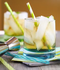 a glass filled with ice and limeade sitting on top of a blue table cloth