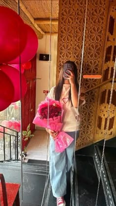 a woman taking a selfie with her cell phone in front of balloons and flowers