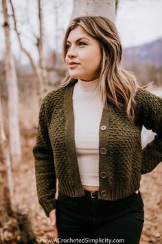 a woman standing next to a tree wearing a green cardigan