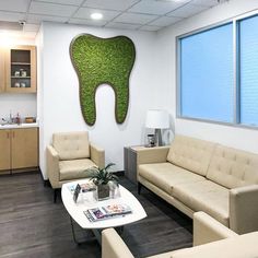 a living room with couches, chairs and a coffee table in front of a green wall