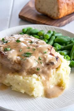 mashed potatoes with gravy and green beans on a plate next to a loaf of bread