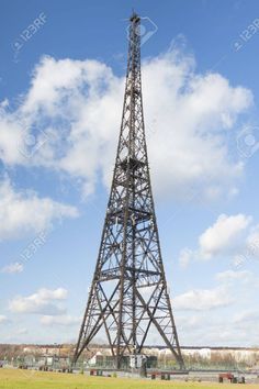 a tall metal tower sitting on top of a lush green field under a blue sky