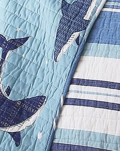 a blue and white quilted bed spread with two dolphins on the front, one in the back