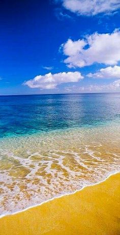 an ocean view with waves crashing on the shore and blue sky in the back ground