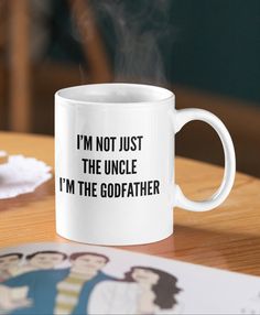 a white coffee mug with the words i'm not just the uncle i'm the godfather on it