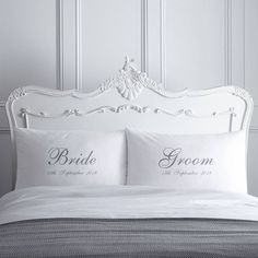 a white bed topped with two pillows next to a wall