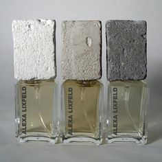 three empty bottles are lined up in front of each other on a white surface,