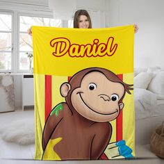 a woman holding up a yellow towel with a monkey on it's face and name