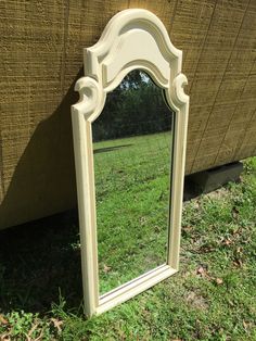 a white mirror sitting on top of a grass covered field