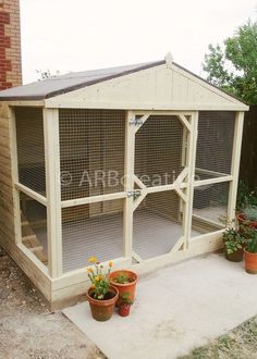 an outdoor chicken coop with plants and potted flowers