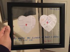 someone holding up a framed map with two hearts