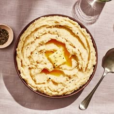 a bowl filled with mashed potatoes next to two spoons