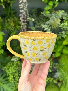 a hand holding up a yellow and white cup with lemons printed on the inside