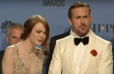 a man in a white tuxedo and a woman in a gold dress at an awards event