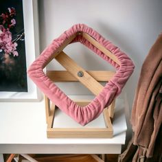 a pink pillow sitting on top of a wooden stand