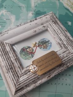 a wooden frame with two gold hearts and a keychain attached to it on top of a map