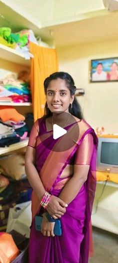 a woman in a purple sari is smiling at the camera and she has her hands on her hips