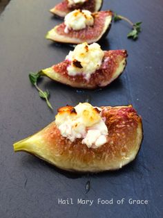 figs with goat cheese and herbs are lined up on a black counter top, ready to be eaten