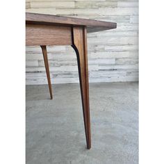 a wooden table sitting on top of a cement floor next to a white brick wall